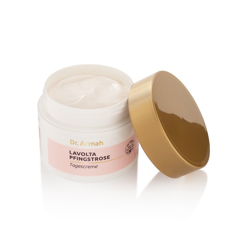 Ein geöffneter Tiegel der Dr. Armah LAVOLTA PFINGSTROSE Tagescreme mit dem goldenen Deckel daneben gelehnt, fotografiert auf einer reflektierenden weißen Oberfläche.